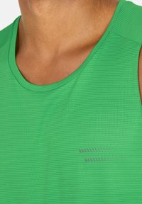 Groene sportieve tanktop van een textuurstof, met een ronde halslijn en subtiele grijze accentlijnen aan de voorkant.