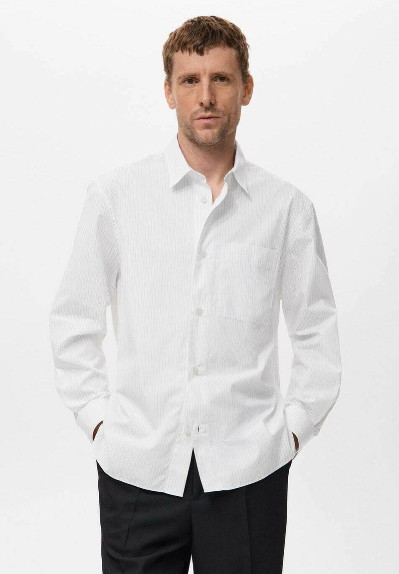 Camisa blanca de manga larga, con botones, con rayas verticales, un cuello puntiagudo y un bolsillo en el pecho. Textura suave, corte ajustado y tejido ligero.