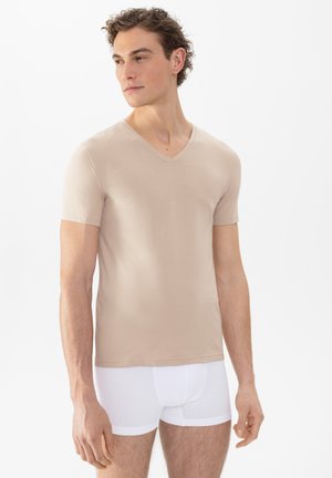 Beige V-Ausschnitt-T-Shirt aus glattem, leichtem Material, mit kurzen Ärmeln und körpernahem Schnitt, kombiniert mit weißen Boxershorts.