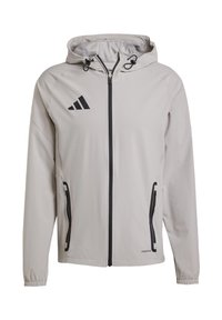 Svijetlosiva sportska jakna s kapuljačom, zatvaranjem na patentni zatvarač sprijeda, crnim akcentima, dva bočna džepa, elastičnim rukavima i brendiranim logom na prsima.