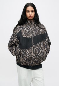 Μπουφάν bomber με animal print σε καφέ και μαύρες αποχρώσεις, με μονόχρωμο μαύρο πάνελ στο στήθος, κλείσιμο με φερμουάρ και ελαστική ραφή στο κάτω μέρος.