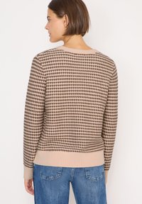 Maglione beige lavorato a maglia con motivo a pois marroni, orlo e polsi a costine, scollatura rotonda e vestibilità comoda. Modello mostrato da dietro.