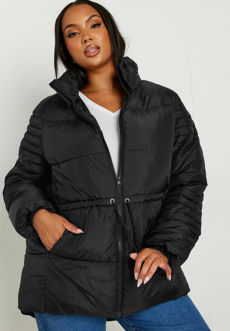 Svart puffjacka med dragkedja fram, hög krage och elastiska ärmslut. Har dragsko i midjan, två sidofickor och kviltad textur.