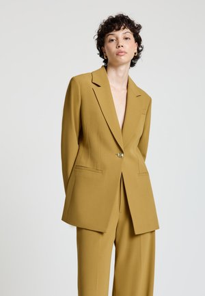 Senfgelber, maßgeschneiderter Blazer mit zwei Vordertaschen, abgestepptem Revers, einfacher Knopfleiste und lockerem Sitz. Glatte Stoffstruktur.