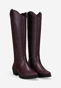 Botas altas de rodilla de cuero vegano en un rico burdeos, con punta afilada, cremallera lateral y bordes en estilo occidental con ondas. Suela negra y detalles de costura.