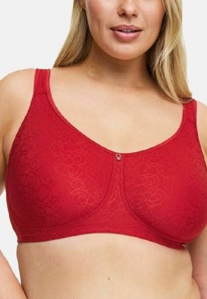 Vrouw draagt een rode, niet gevoerde beha met subtiele bloemmotieven en een klein centraal decoratief hangertje op een witte achtergrond.