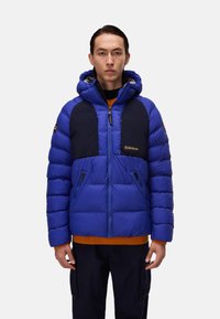 Giacca puffer blu con cappuccio, caratterizzata da pannelli blu navy, tasche con zip e polsini in maglia arancione. Visibile la zip frontale e il dettaglio del logo.