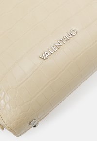 Beige leather clutch with a crocodile texture, featuring silver "Valentino" logo and metallic hardware accents. Select stitching detail visible.