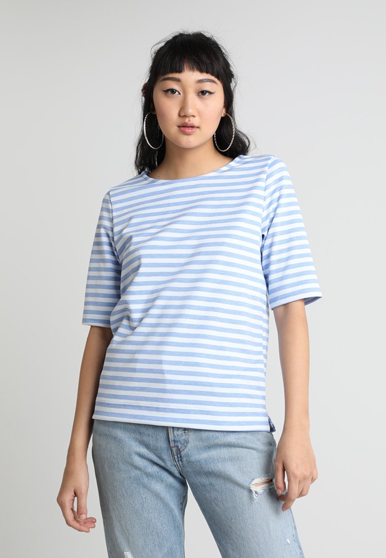 Lyseblå stribet T-shirt i blødt bomuldsstof, med bred udskæring og korte ærmer. Sammen med slidte lyse denimjeans.