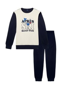 Completo pigiama in due pezzi con top crema dalle maniche blu navy e stampa grafica con la scritta "APRES SKI Social Club", abbinato a pantaloni blu navy.