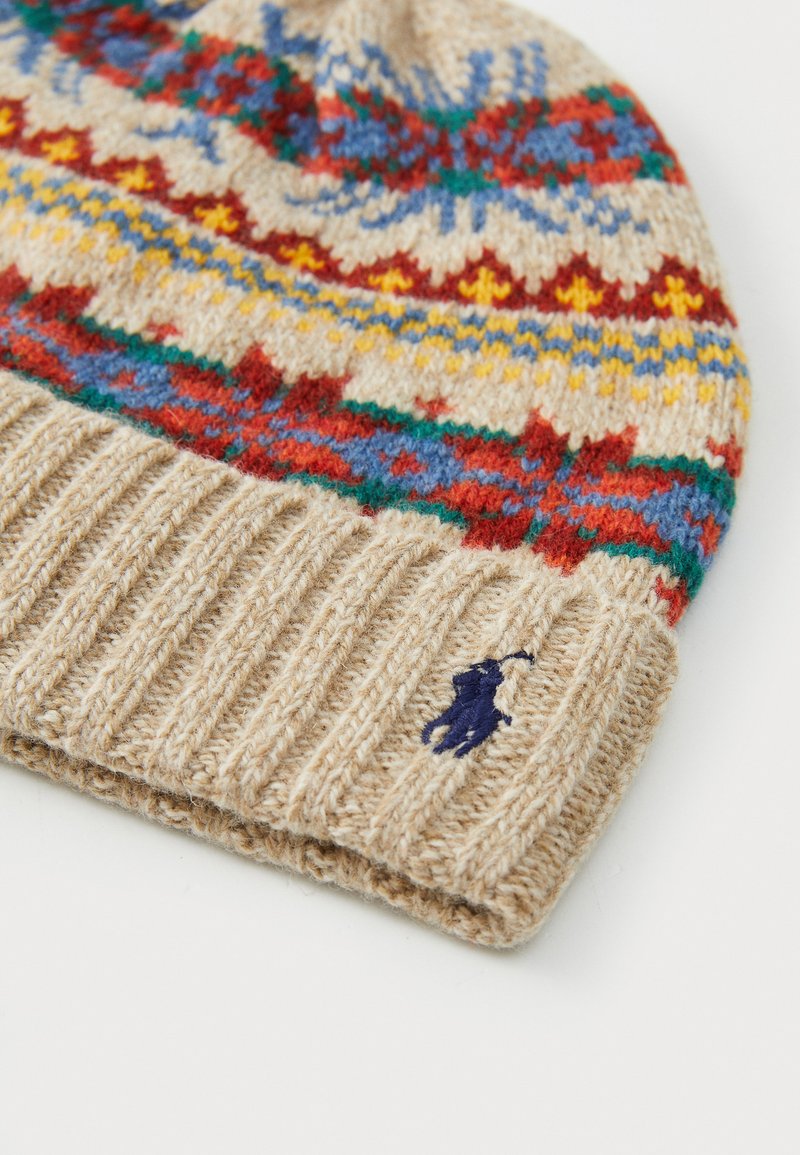 Gehaakte beanie in beige met meerkleurige patronen, voorzien van rode, blauwe en gele accenten. Geribbelde manchette en geborduurd logo.
