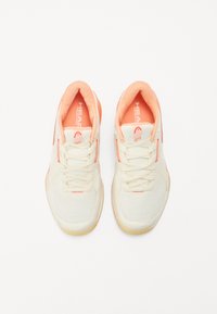 White sneakers with peach accents, mesh upper, and rubber sole. Features flat laces and logo on the tongue and side.