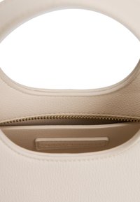 Beżowa torebka wykonana z teksturowanej skóry, z okrągłym uchwytem w formie wycięcia oraz zamykanym na suwak wewnętrznym przegrodą z zamkiem w kolorze złotym.