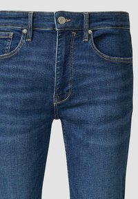 Dunkelblaue Jeans aus Denim mit Standardpassform. Merkmale sind fünf Taschen, ein Knopfverschluss und dezente Nähakzente. Glatte Textur.