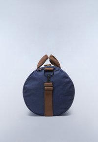Borsa da viaggio rotonda blu navy con manici marroni e tracolla regolabile su sfondo grigio chiaro.