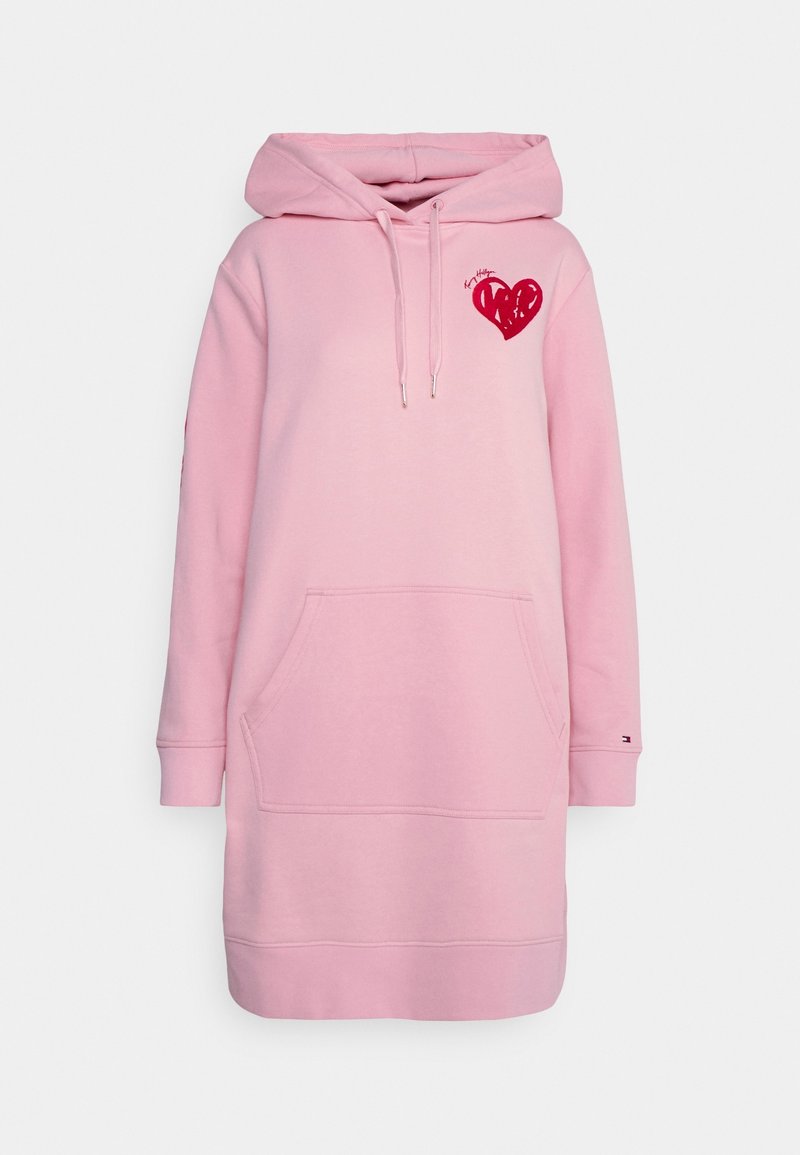 Robe sweat à capuche rose clair avec poche frontale, motif cœur rouge sur la poitrine, et capuche avec cordon, sur fond blanc.