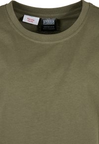 Olive zelené bavlnené tričko s okrúhlym výstrihom, na ktorom je štítok s nápisom "URBAN CLASSICS" a pokynmi na údržbu. Mäkká textúra.