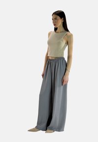 Beige mouwloze crop top gecombineerd met lichtgrijze wijde broek met een elastische tailleband. Glad stof, minimalistisch ontwerp.