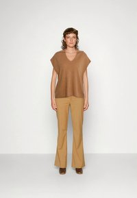 Top castanho de gola em V e mangas curtas, combinado com calças acampanadas em tom bege, criando uma silhueta descontraída. Tecido suave com uma textura subtil.