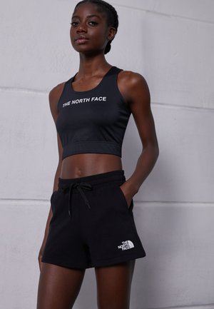 Top corto atlético negro con el logo de "THE NORTH FACE", combinado con pantalones cortos negros con cordón que presentan un logo blanco en la pierna izquierda.