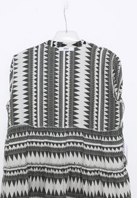 Svart-vit mönstrad klänning med geometrisk design, med rund halsringning och rynkad midja. Tyget är slätt och lätt.