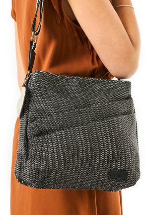 Schwarze und weiße strukturierte Schultertasche in rechteckiger Form, mit einem Reißverschlussverschluss und einem Logoshild. Verstellbarer Trageriemen angebracht.