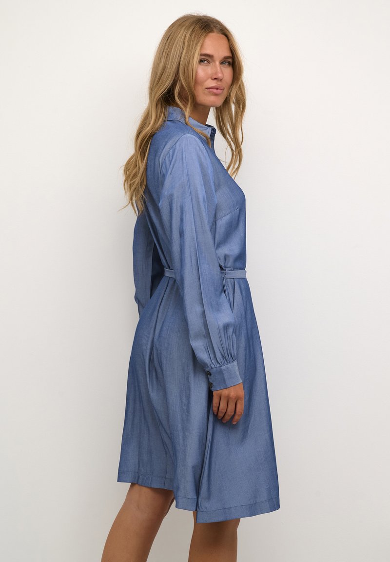 Blaues Jeanshemdkleid mit langen Ärmeln, Knopfmanschetten, einem Kragen und einem Bindegürtel in der Taille. Glatte Textur und knieumspielendes Design.