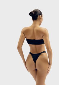 Černý bandeau bikinový top s nabíranou texturou; odpovídající spodní část ve stylu thong s nízkým pasem. Hladká tkanina s minimálním pokrytím, vhodná pro plavky.