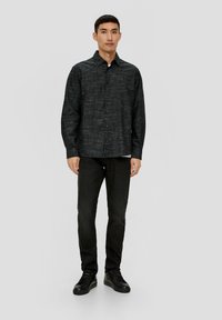 Zwart gestreepte longsleeve shirt met een knoopsluiting aan de voorkant, gecombineerd met zwarte slim-fit broek en zwarte veterschoenen.
