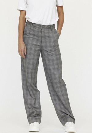 Pantalons à carreaux gris avec une coupe évasée, en tissu doux, avec des poches latérales, associés à un t-shirt blanc uni et des baskets blanches.