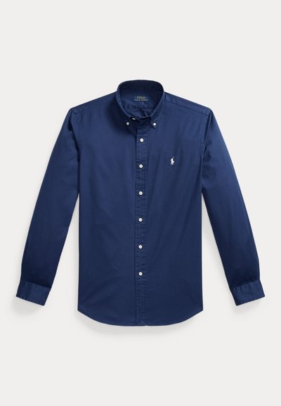 Chemise bleu marine à manches longues avec boutons, col, boutons blancs et petit logo blanc brodé sur la poitrine gauche.