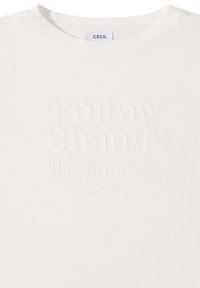 T-shirt blanc avec texte en relief "Follow Change Dance" et texte plus petit "Vis ta propre vie, poursuis ta propre voie," avec étiquette CECIL à l'intérieur du col.