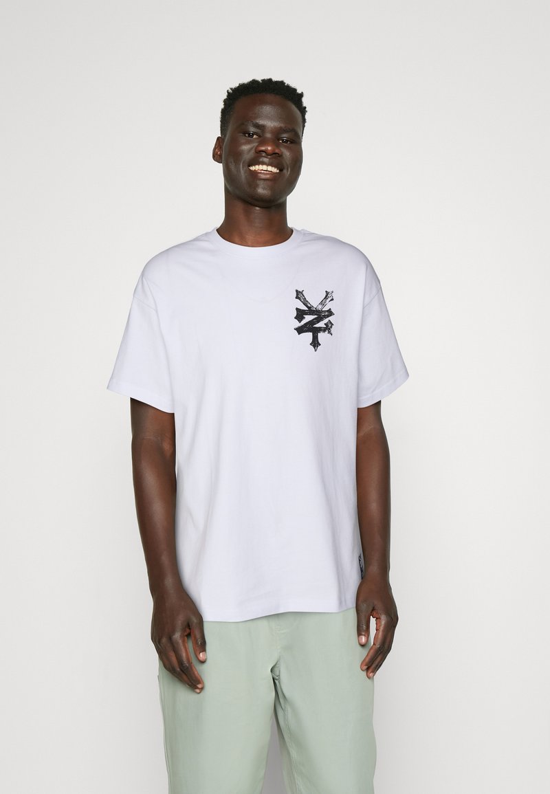 Hvid bomulds t-shirt med rund hals og korte ærmer, prydet med et sort grafisk design på venstre brystområde.