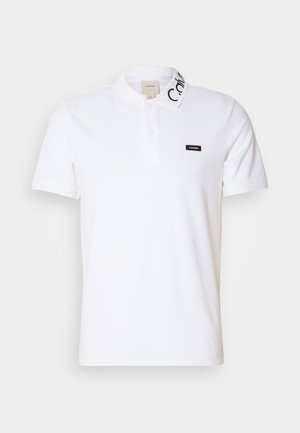 Weißes Polo-Shirt aus Baumwolle mit einem Kragen mit Knöpfen und einem schwarzen Markenlabel auf der linken Brust. Der Kragen hat schwarze Akzentnähte.