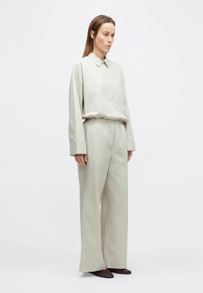 Chemise gris clair avec patte de boutonnage et poche poitrine, associée à un pantalon large assorti. Tissu lisse avec un motif à fines rayures subtile.