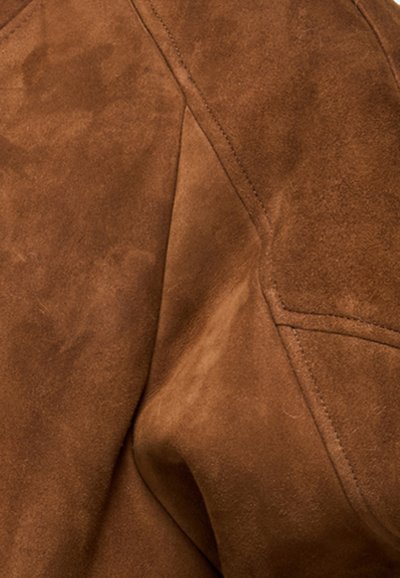 Tâmplă de suede maro cu o textură moale, pliată, cu cusături vizibile și detalii de design unghiulare. Fără modele sau accesorii vizibile.