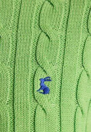 Grønt strikket stof med kabelmønster og lille broderet blå kanindetalje i midten.