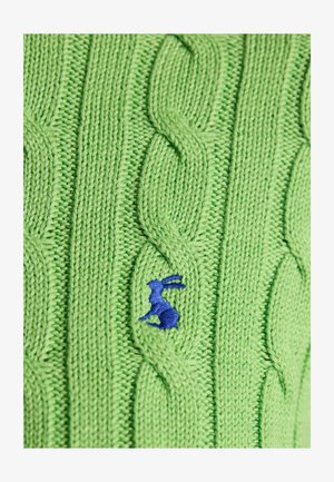 Grønt strikket stof med kabelmønster og lille broderet blå kanindetalje i midten.