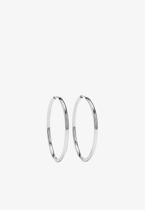 Para cienkich, błyszczących srebrnych kolczyków-kołeczków z prostym zapięciem, przedstawionych na białym tle.