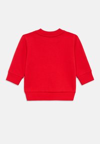 Rød genser med lange ermer, ribbestrikkede mansjetter og rund hals. Jevn tekstur med et enkelt, ensfarget design.