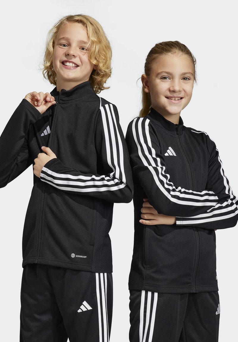 Zwarte sportjacks met witte drie-streep accenten, hoge kragen, ritsvoorkanten en een textuurstof met het "AEROREADY" logo aan de onderkant.
