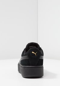 Sneaker nera in suede con strisce grigie e logo dorato. Design a profilo basso con superficie testurizzata e suola nera spessa.