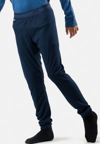 Pantaloni termici a coste blu con un cinturino logo. Design aderente, texture liscia e cuciture scure a contrasto, adatti per il clima freddo.