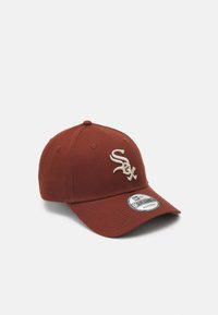 Casquette de baseball rouge en tissu avec un visière incurvée, présentant un logo blanc brodé à l'avant et une étiquette de marque sur le bord.