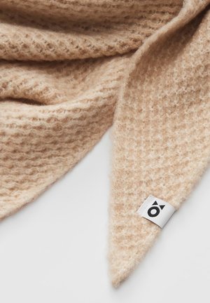 Écharpe en tricot beige avec une finition douce et texturée. Présente une pointe triangulaire et une étiquette blanche avec un logo noir.