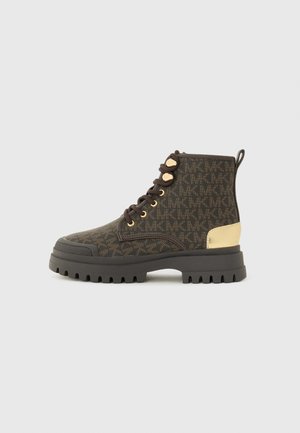 Bottines marron à motif avec des accents dorés, semelle en caoutchouc et bout rond. Elles possèdent un laçage et une languette à l'arrière.