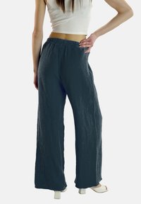 Wijde donkerblauwe broek gemaakt van textiel met een elastische tailleband. Gecombineerd met een witte cropped top en platform sandalen.