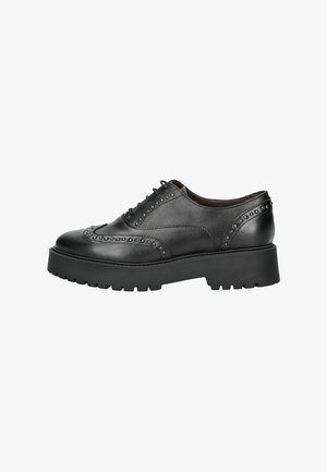 Zwarte leren brogue schoen met dikke profielzool en metalen studs langs de naden en teenkap, zijaanzicht.