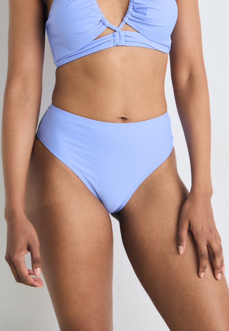 Lys blå bikini med en samlet topp som har et utskjæringsdetalj, og høy midje-bunner. Laget av glatt, elastisk stoff.