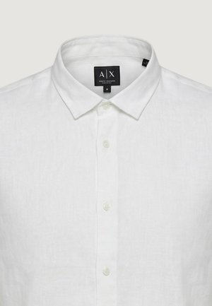 Biała lniana koszula z długim rękawem, z zaostrzonym kołnierzem i białymi guzikami, metka z marką A|X Armani Exchange oraz rozmiarem medium.